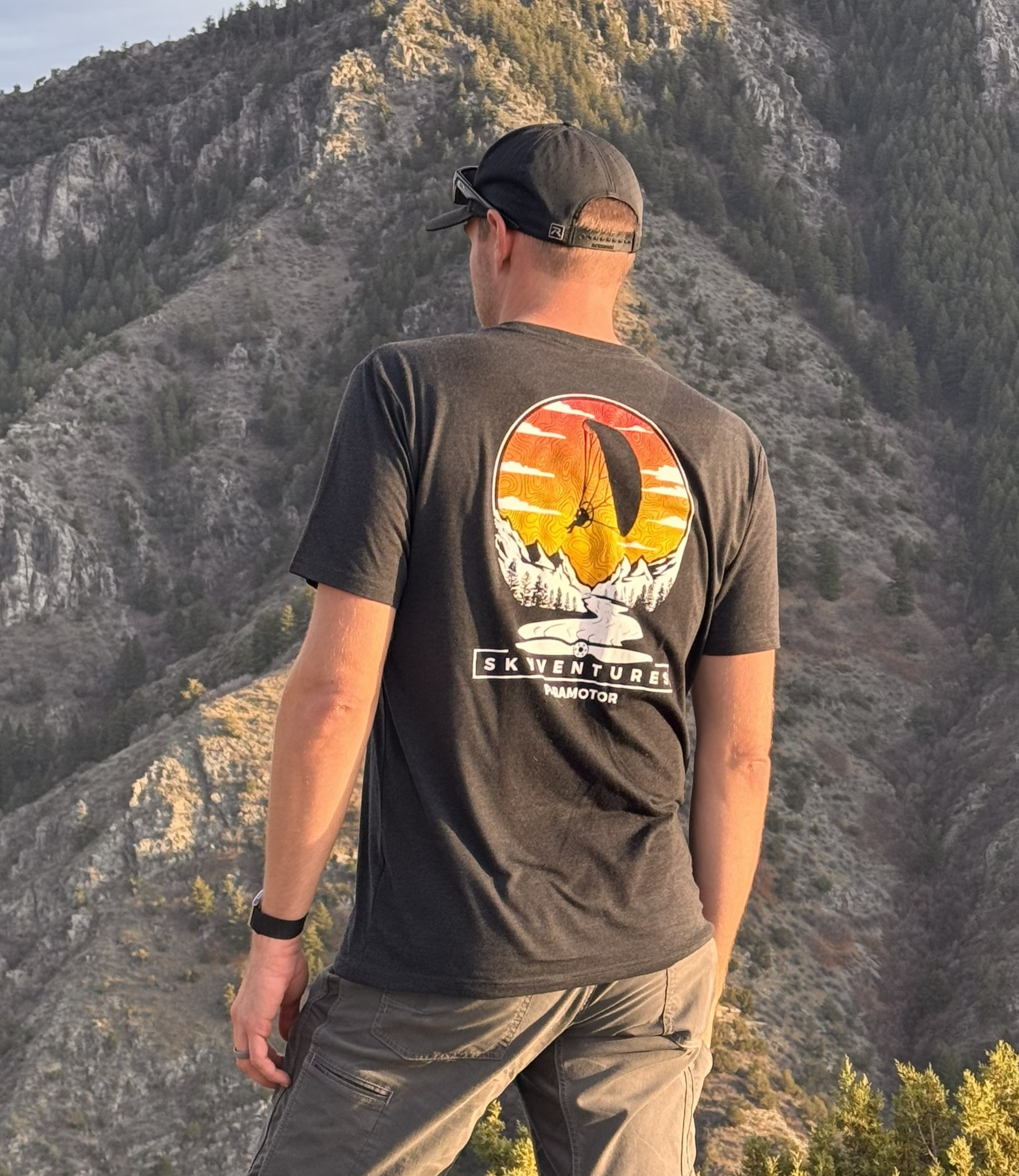 Person wearing a t-shirt with a mountain design in a natural setting